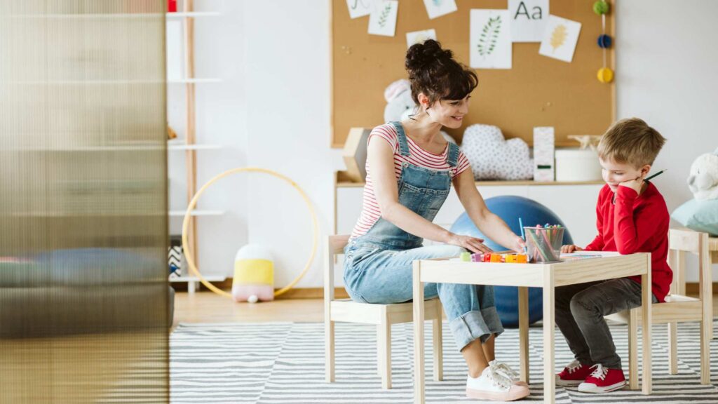 A child with his therapist in a playroom, showing a calm learning moment to explain different levels of autism support.