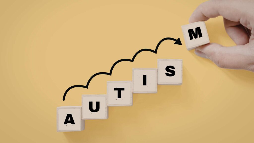 A set of wooden blocks spelling AUTISM, with each block at different levels, to illustrate the levels of autism