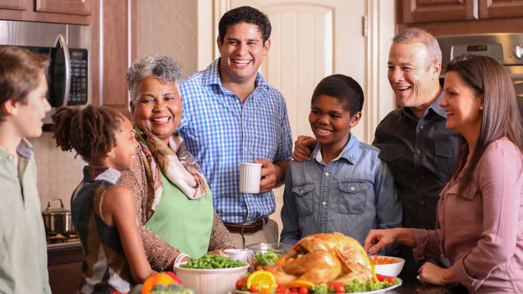 Family and friends smiling together in the kitchen while preparing Thanksgiving dinner, illustrating autism-friendly holidays built on inclusion and understanding.