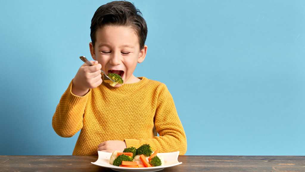 Child eating vegetables despite autism food aversion challenges