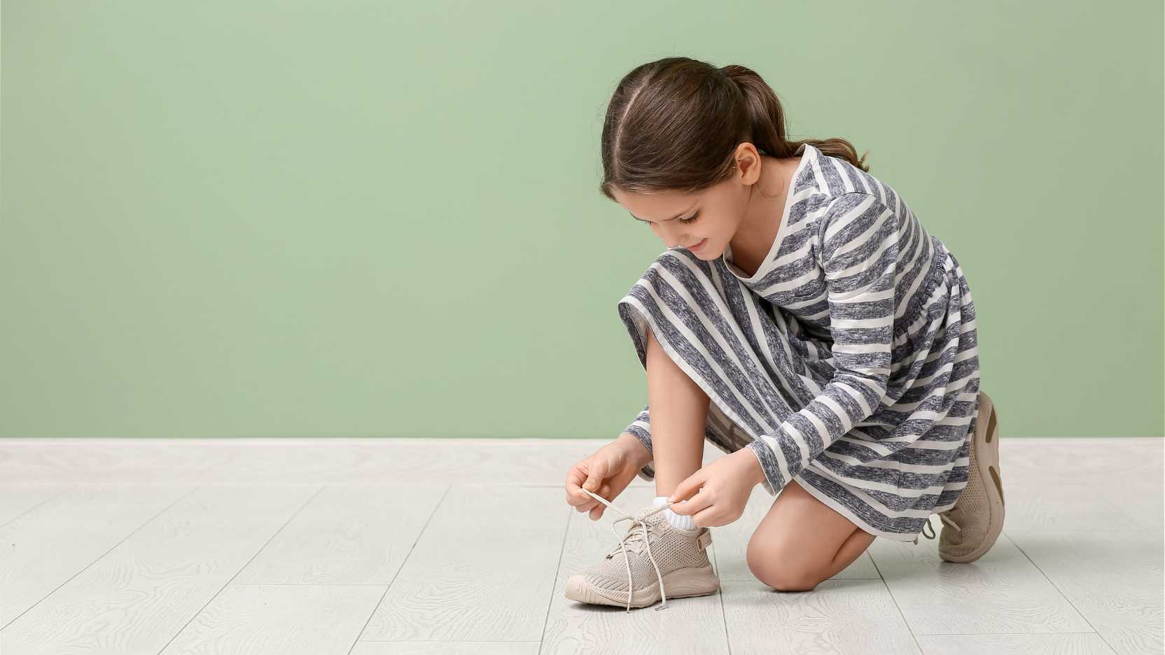 Child learning independence through autism daily living skills like tying shoes